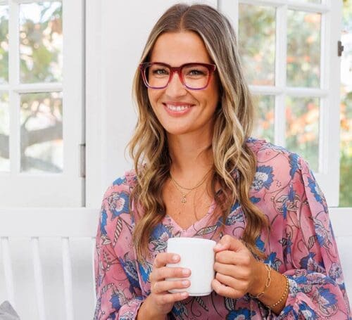 Woman in glasses holding coffee cup.