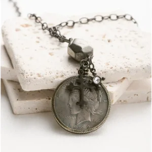 close-up coin-like pendant and small cross on necklace