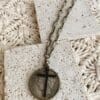 necklace with coin-like pendant and black cross pendant