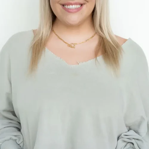 Woman wearing a gold toggle necklace.