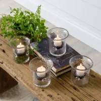 Four glass candle holders with tea lights.